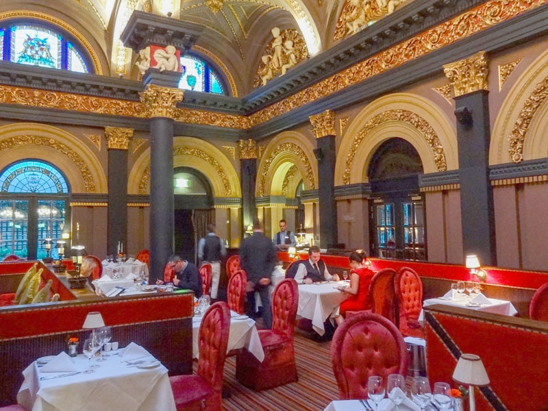 people dining in a very ornate restaurant with red furniture and gold on the walls