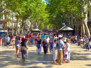 people walking under trees along a large pedestrian boulevard
