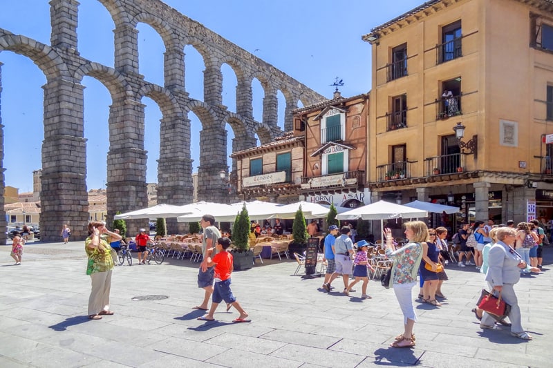 people taking photos at an ancient Roman aqueduct seen when you visit on day trips from Madrid