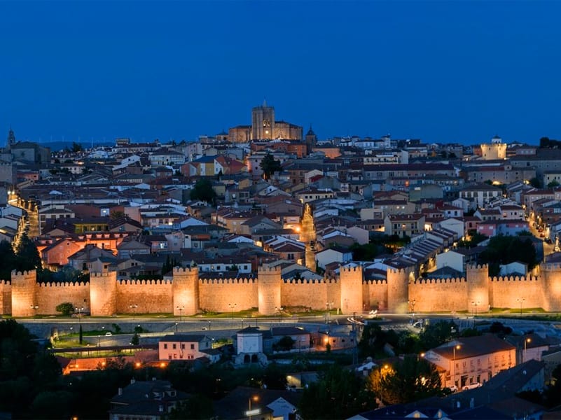 an ancient walled city with its city walls lit up at night