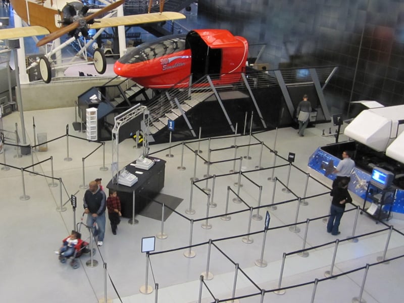 people near flight simulators in a museum