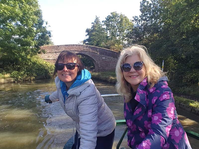 two women steering a canal boat on a river