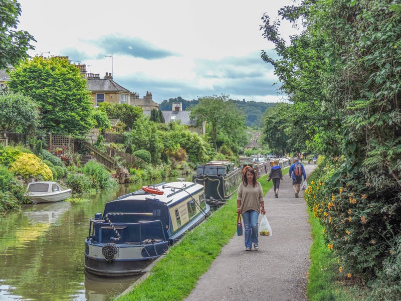 a woman walking past boats moored by a path