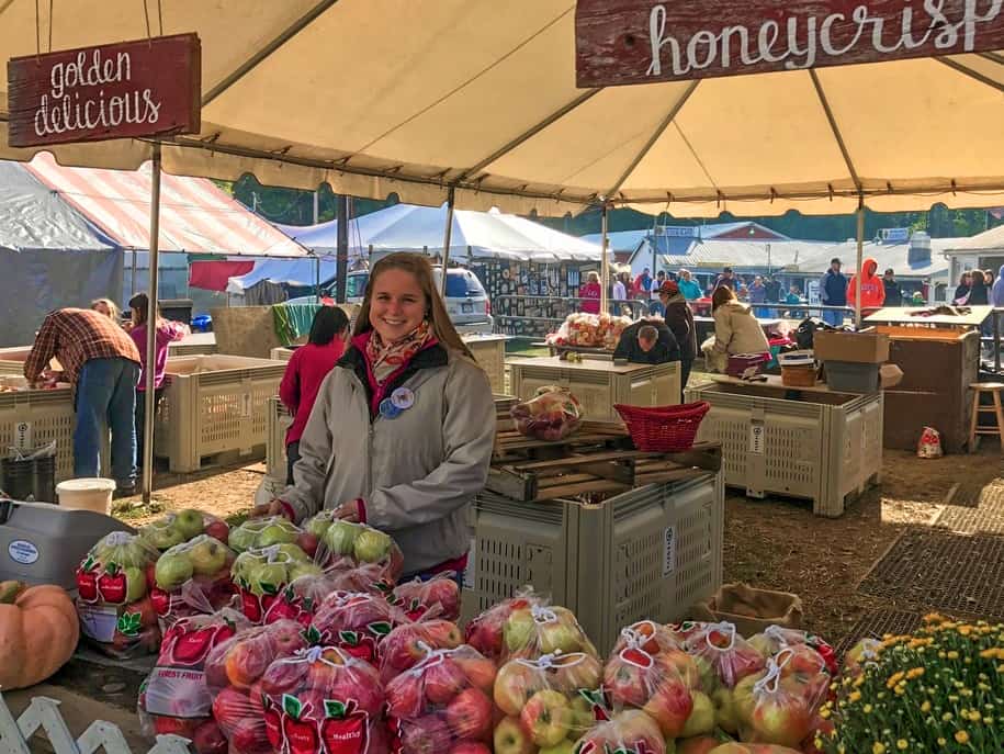 a young woman selling apples at a fall festival