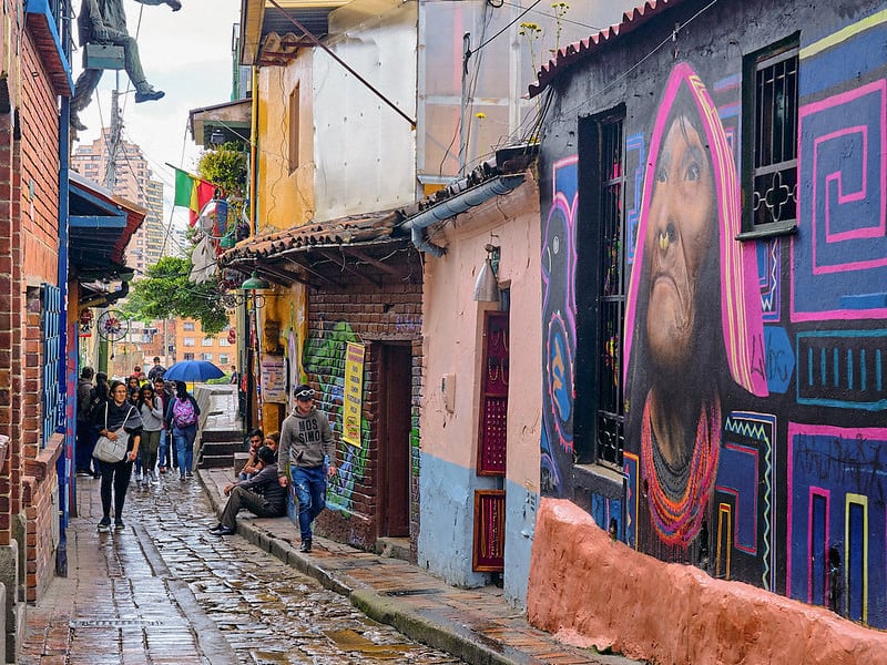 people walking by Bogotá's Street Art on a narrow street