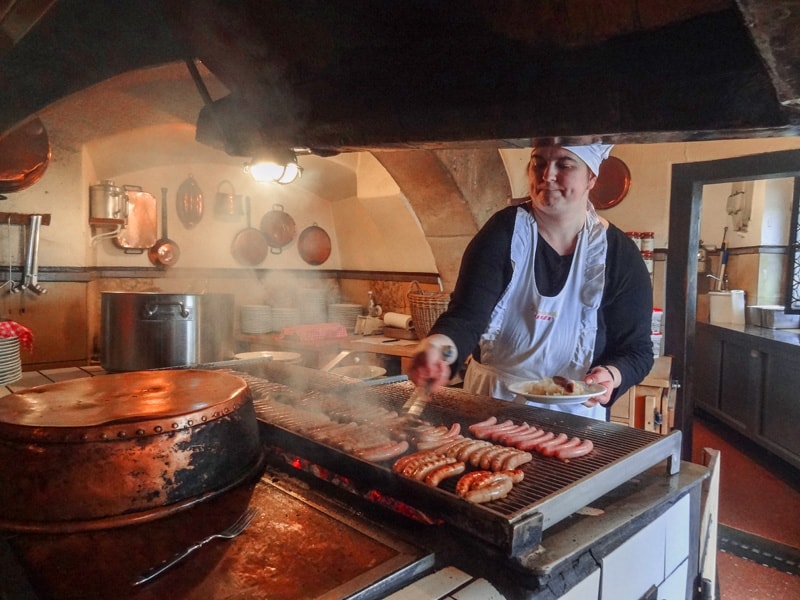 a woman grilling wursts in a restaurant in Germany