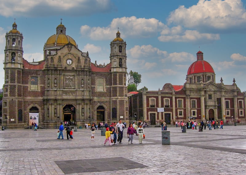 people walking across a vast square in front of a basilica - one of the places to visit in Mexico City