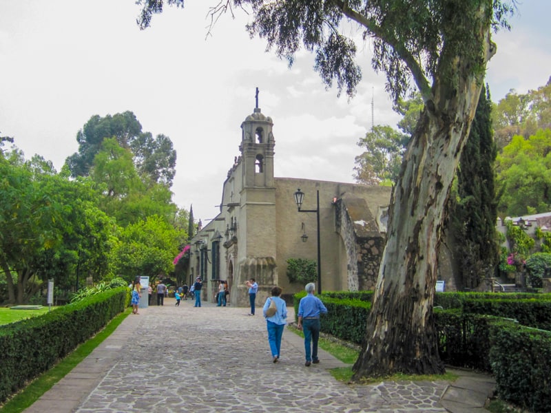 people walking by an old church - one of the places to visit in Mexico City