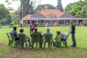 people sitting in lawn chairs outside a large house