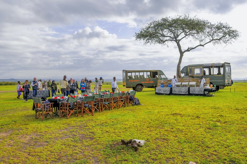 tables set up for breakfast near a tree where there are two Range Rovers