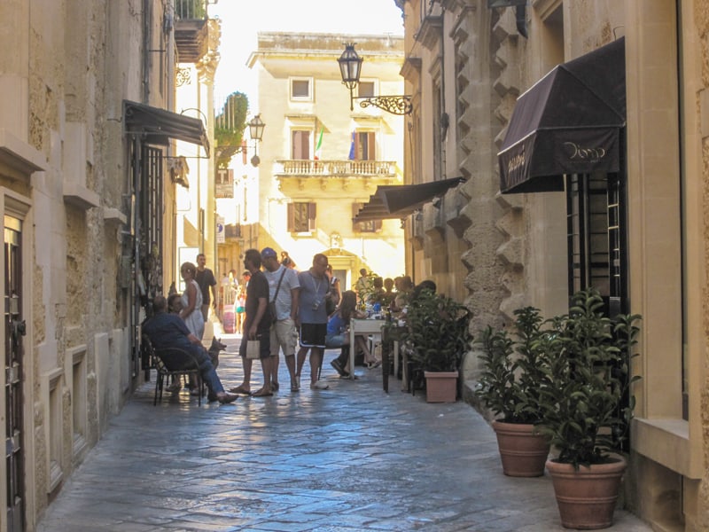 people walking along an old street at sunset