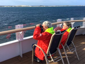 people with binoculars sitting on the deck of a ship