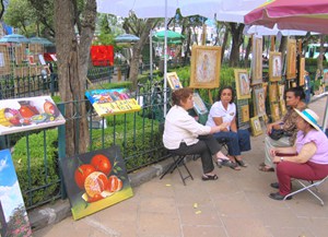 four women having a conversatiuon at an art fair in a park