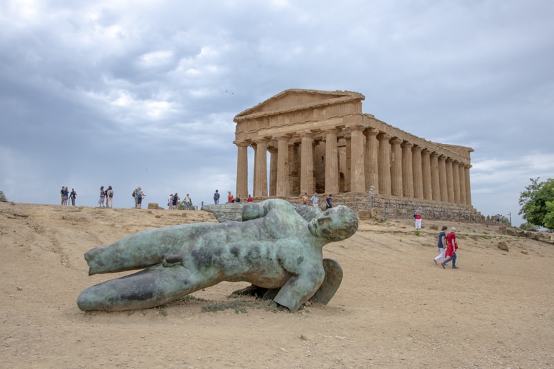 an old statue laying on the ground in front of an ancient temple