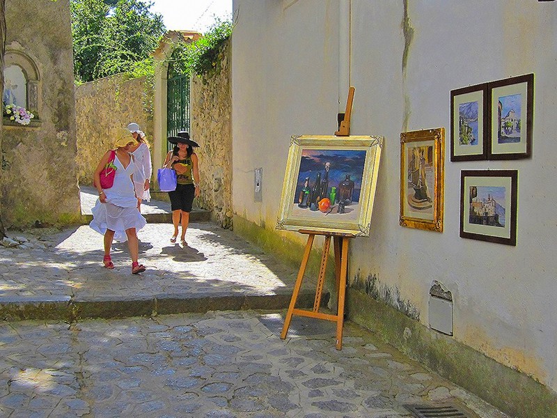 women walking by paintings on a street wall in Ravello - one of the Top 10 Places to Visit in Italy