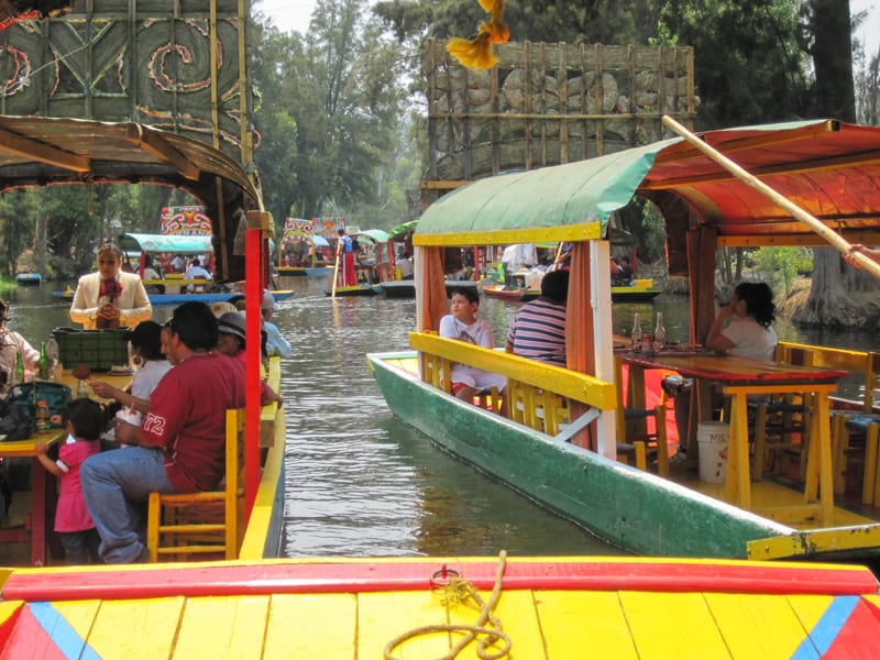 people on very colorful boats on a lake and canal