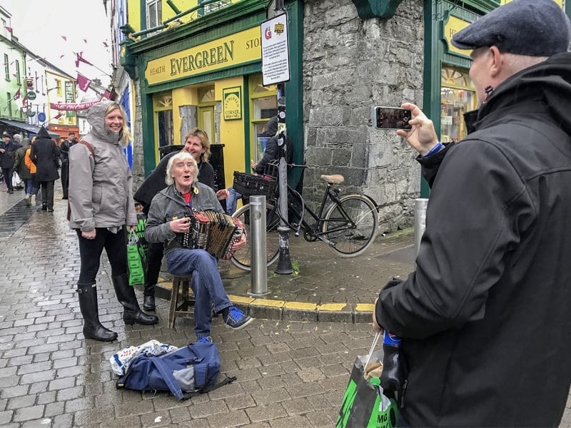 people taking a photo of a street musician in Galway the most Irish town in Ireland
