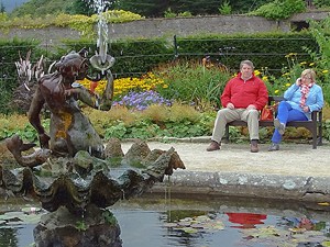 a couple sitting on a bench by a pool surrounded by flowers