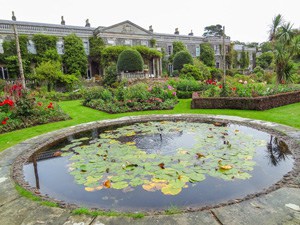 a pool in front of an old house with beautiful landscaping