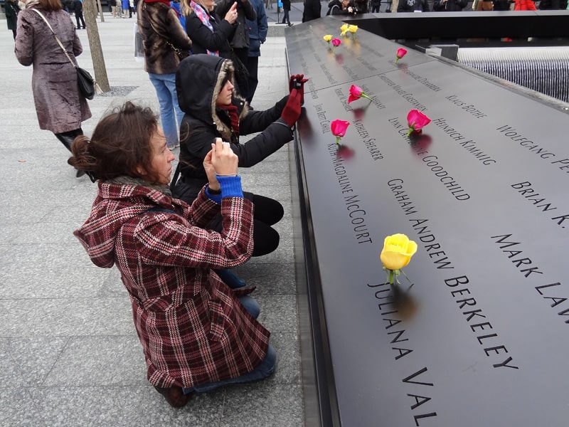 women taking photos of victims names at the 911 Memorial in New York in winter