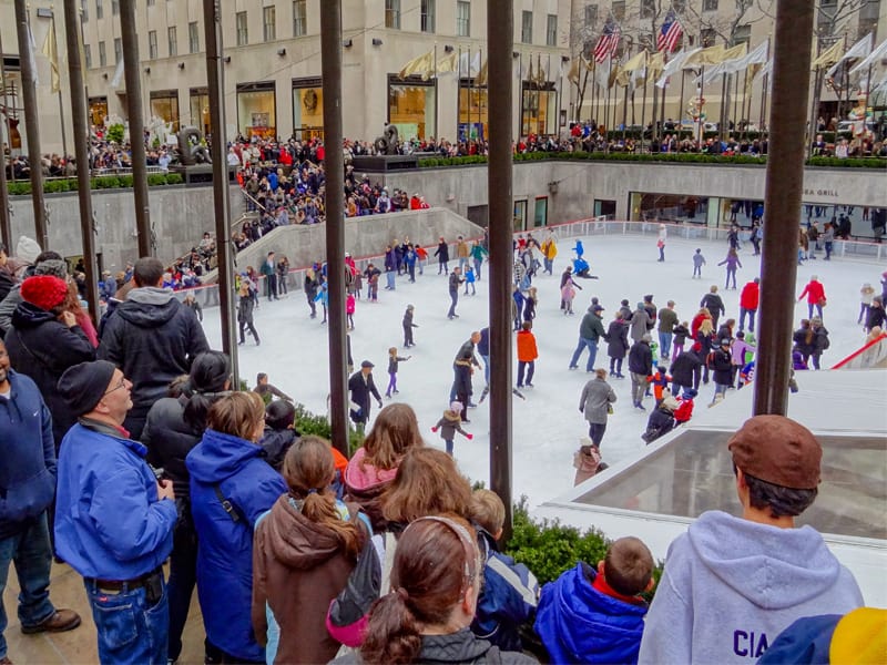 people looking at skaters at the Rockefeller Center skating rink in New York in winter