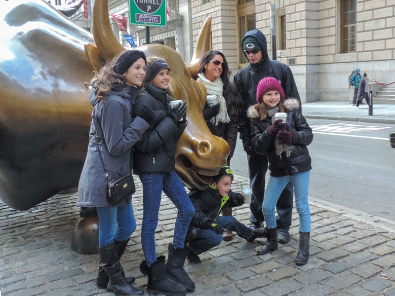 a family having their photo taken by a large statue of a bull on Wall Street