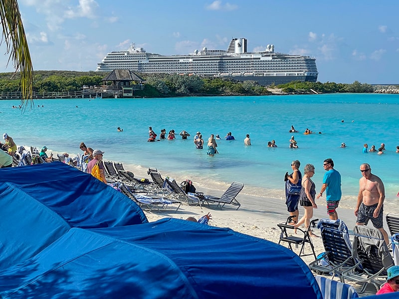 people on a beach near a docked cruise ship