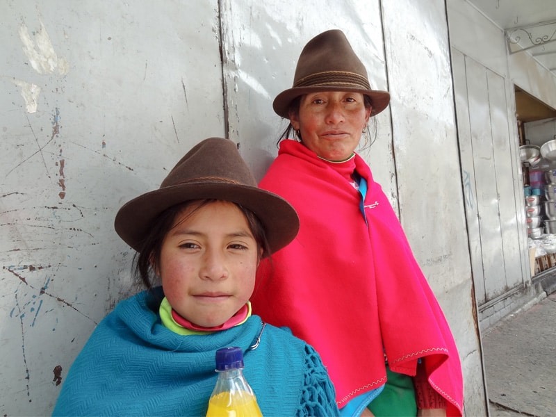 an indigenous  woman and her daughter with hats and brif=ghtly colored capes in Cuenca, one of the top places to visit in Ecuador
