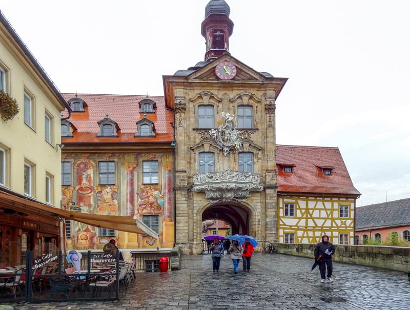 people with umbrellas walking by a beautiful old building – one of the things to do in Bamberg, Germany