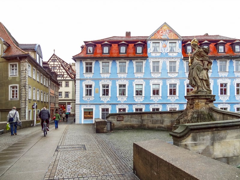 People walking past a wedwood colored building – one of the things to do in Bamberg, Germany