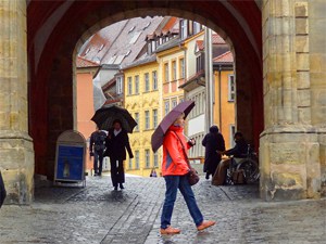 a woman with an umbrella walking by an archway