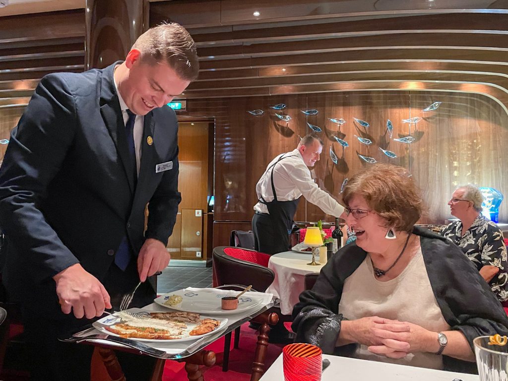 a waiter deboning a fish table-side in athe ship's restaurant