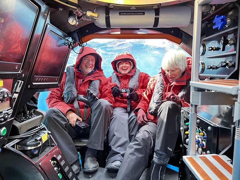 people in red jacket sitting on a small submarine