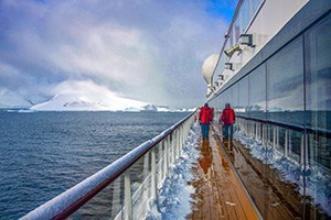 a person in a red jack walking on a ship's deck while on an expedition in Antarctica