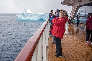 a woman taking a photo from a ship's deck on an expedition in Antarctica