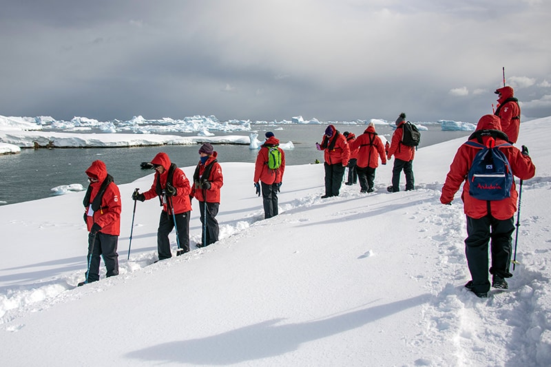 people in red jackets walking through the snow on an expedition in Antarctica