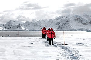 people in red parkas walking in snow - clothing for Antarctica
