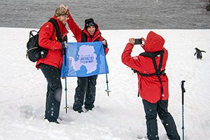people holding blue banner while having their photo taken during an expedition in Antarctica