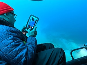 a man looking at his cell phone camera in front of a blue wall