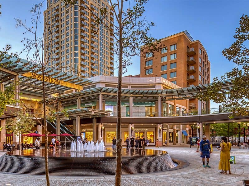 people walking about a fountain in an upscale mall