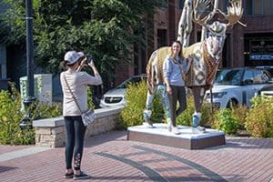 two women taking a photo by a statue of a moose, one of the things to do in salt lake city