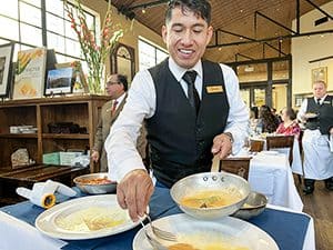 a waiter preparing food at a table