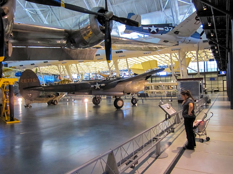 a woman reading a sign about airccraft in front of her in the Air Space Museum Dulles