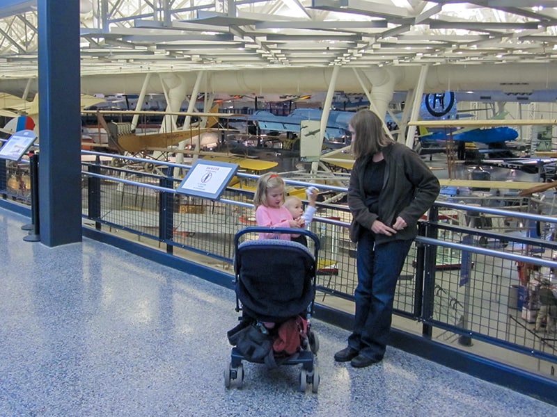 a mother with small children viewing aircraft in a hanger