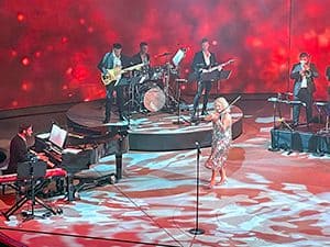 a violinist and an orchestra in front of a bright red background