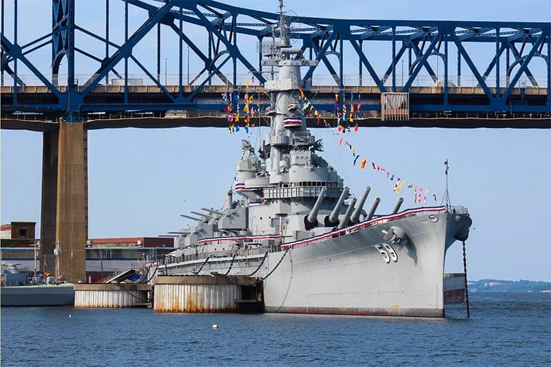 a battleship, a museum ship in the U.S. at a pier under a bridge