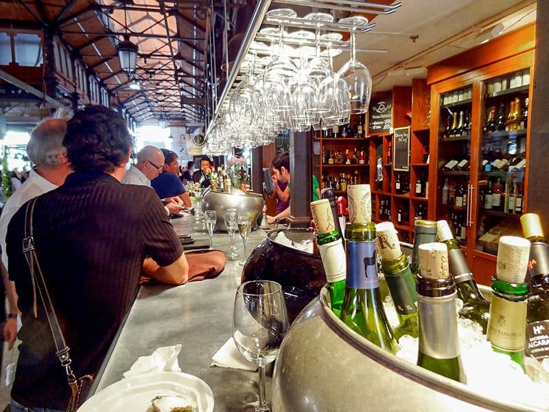 people sitting at a bar in Mercado San Miguel - one of Madrid's Hidden Gems