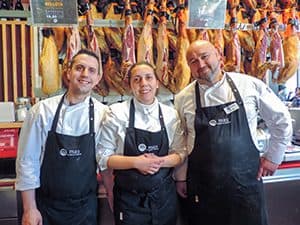 3 butchers at a ham market in Mercado San Miguel - one of Madrid's Hidden Gems