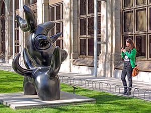 a woman photographing a large statue outside a museum