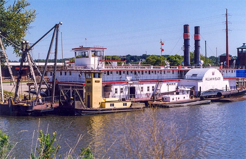a steam-powered dredge moored at a dock